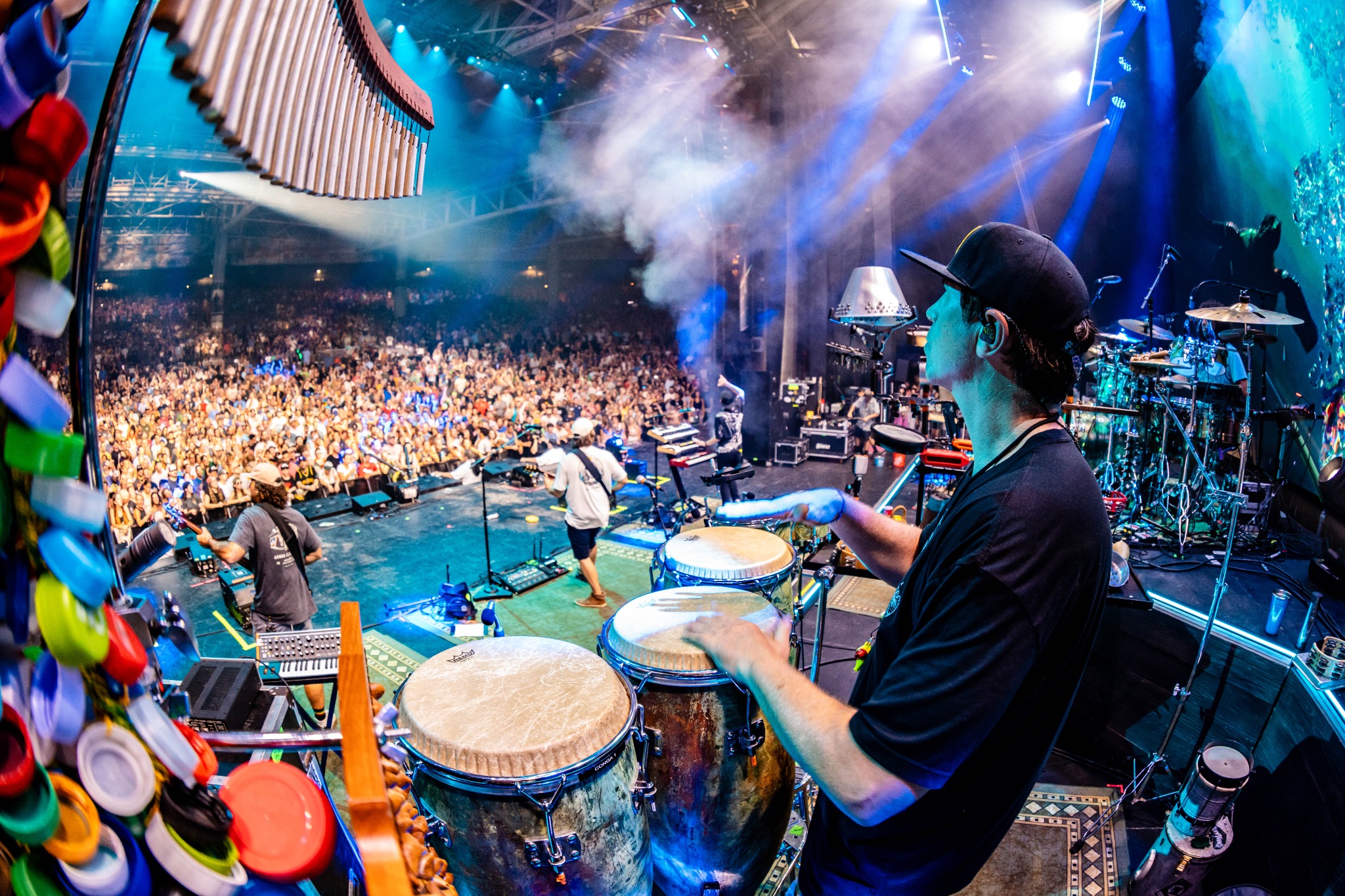 Will Phillips playing congas with his touring percussion rig in front of a large crowd